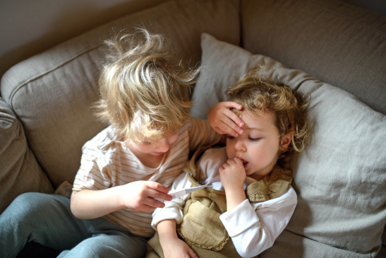 Zwei Kinder mit Fieberthermometer